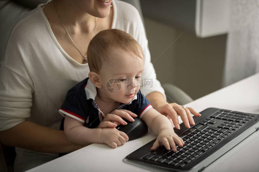 与母亲坐在办公桌后并打电脑键盘打字的图片