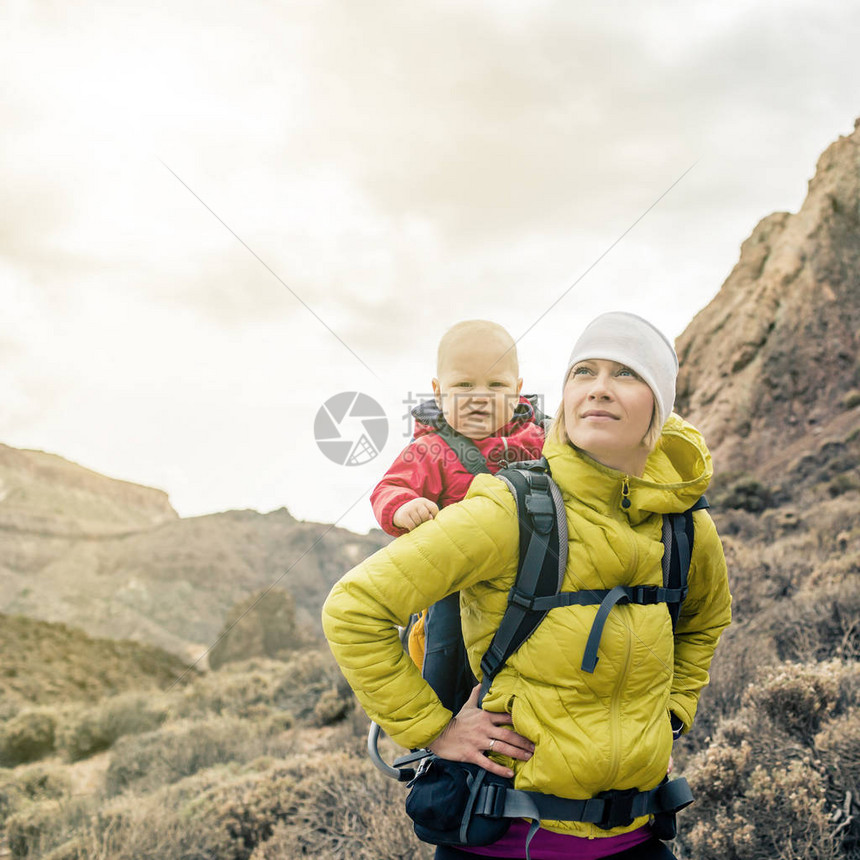 超级英雄妈带着小男孩背着包旅行与孩子一起在山区进行家庭旅行的远足冒险带婴儿的假期旅行图片