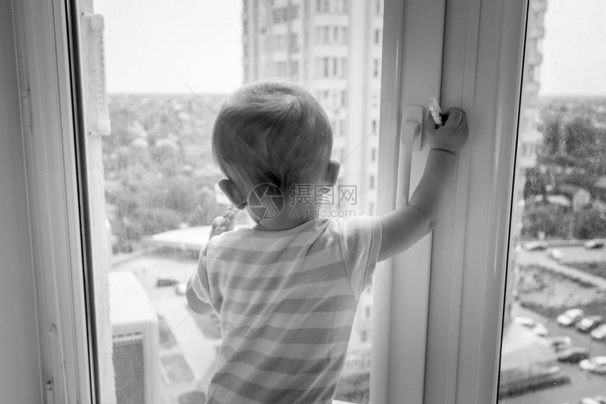 婴儿拉车窗把手并试图打开的黑白照片图片