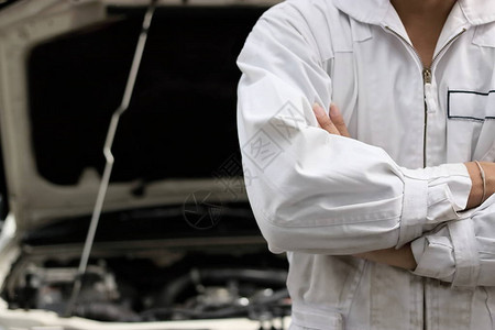 穿着制服的自信职业机械师在修理车库兜帽穿过自己的手臂汽车保险的概念图片