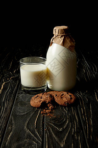 巧克力饼干玻璃新鲜牛奶和用黑底纸包装的瓶装图片