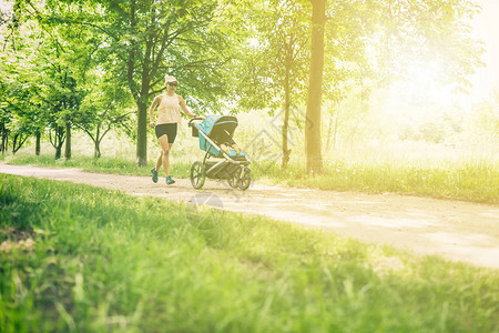 带着婴儿车在公园里享受夏日的跑步女人图片