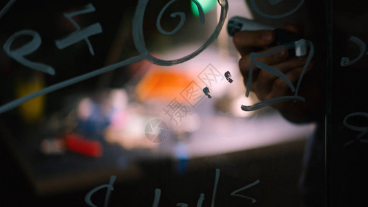 一个人在玻璃白板上写公式的特写镜头库存一位科学家在玻璃配方上写图片