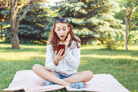 年轻担心白种人少女的肖像与她的手机在公园外面有手机的图片
