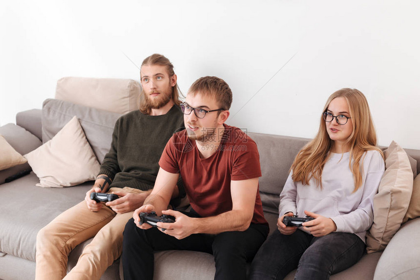 坐在沙发上和在家里一起玩电子游戏的一群朋友在家中坐着图片
