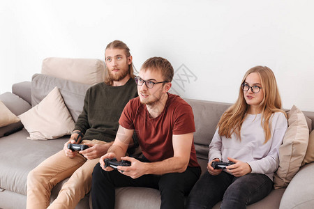 坐在沙发上和在家里一起玩电子游戏的一群朋友在家中坐着图片