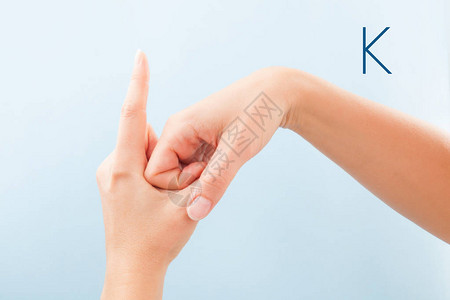 女用蓝色背景孤立的手显示聋哑人BSL字母K高清图片