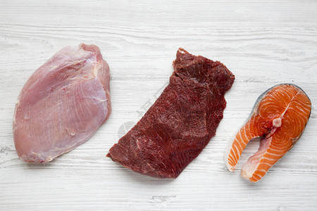 原鲑鱼牛排牛肉和火鸡乳在白木背景图片