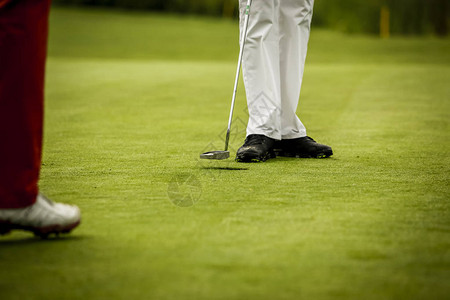 高尔夫球手的腿在洞附近的果岭上背景图片