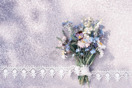 铃兰和野花束放在花边框架中的旧质朴银色桌子上图片