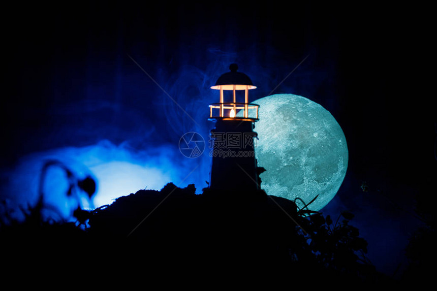 有光束的灯塔在有雾的晚上站在山上的旧灯塔餐桌装饰色调的背景月光图片