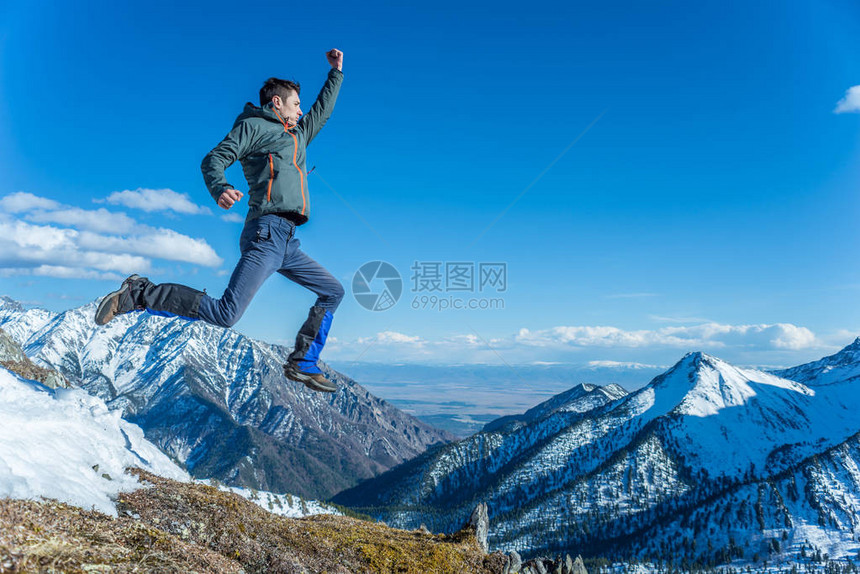男子旅游徒步旅行者在雪山背景下跳高冒险自由和积极生图片