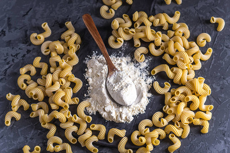 未煮过的意大利面食cavatappi与硬质小麦面粉在深色背景上食品设图片