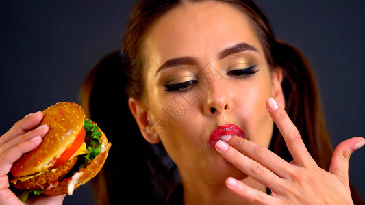 女人吃汉堡女孩想吃汉堡胃口好的肖像人在黑色背景上贪婪地享用美味的三明治教养图片