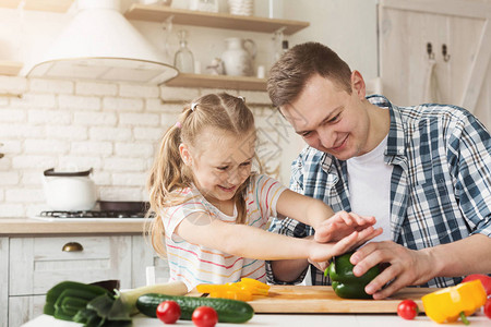 快乐的小女孩和她爸在家厨房做饭图片