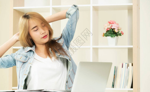 放松的年轻女在工作结束后会伸展手臂和肩膀肌肉图片