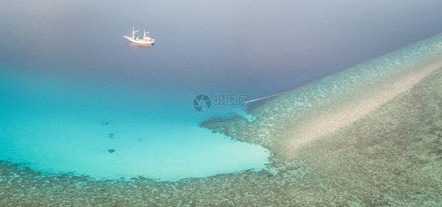 一艘小型皮尼西帆船在印度尼西亚弗洛雷斯附近的美丽珊瑚礁附近航行这个位于珊瑚三角区内的偏远热带地区拥有非凡的海图片