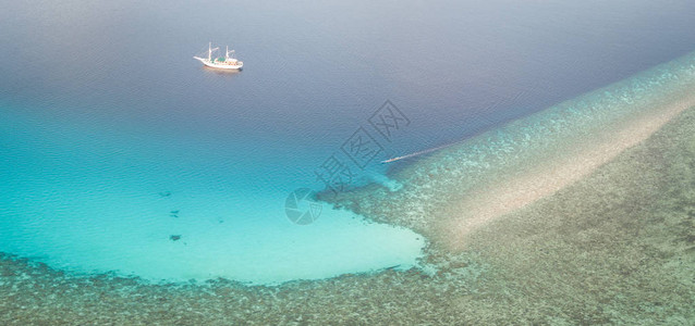 劳伦巴考尔一艘小型皮尼西帆船在印度尼西亚弗洛雷斯附近的美丽珊瑚礁附近航行这个位于珊瑚三角区内的偏远热带地区拥有非凡的海背景