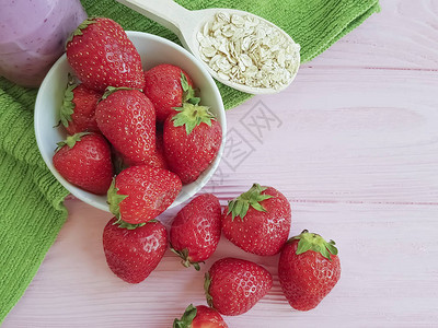 粉红色木质背景中的燕麦冰沙草莓图片