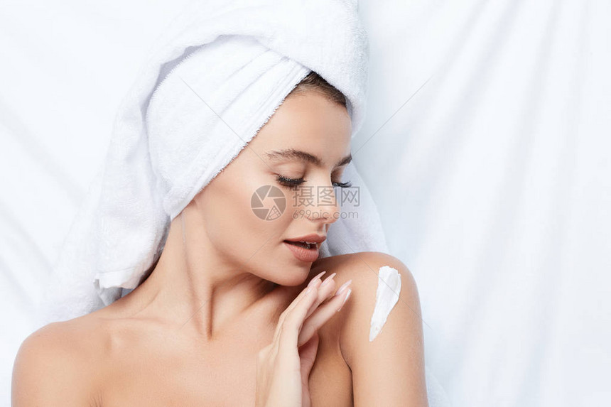 美丽的微笑的年轻女子在白背景使用奶油头部毛巾美容照片皮肤护理图片