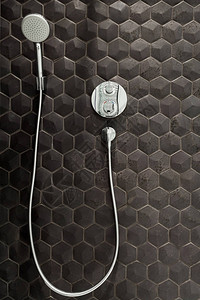 浴室新的淋雨头在黑色瓷砖背景下图片