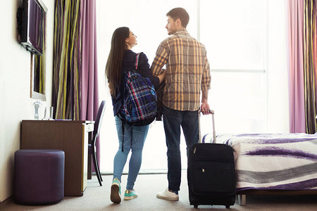 年轻快乐的夫妇带着行李在酒店房间里图片