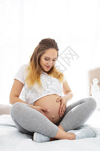 婴儿运动快乐的孕妇坐在床上抚摸肚图片