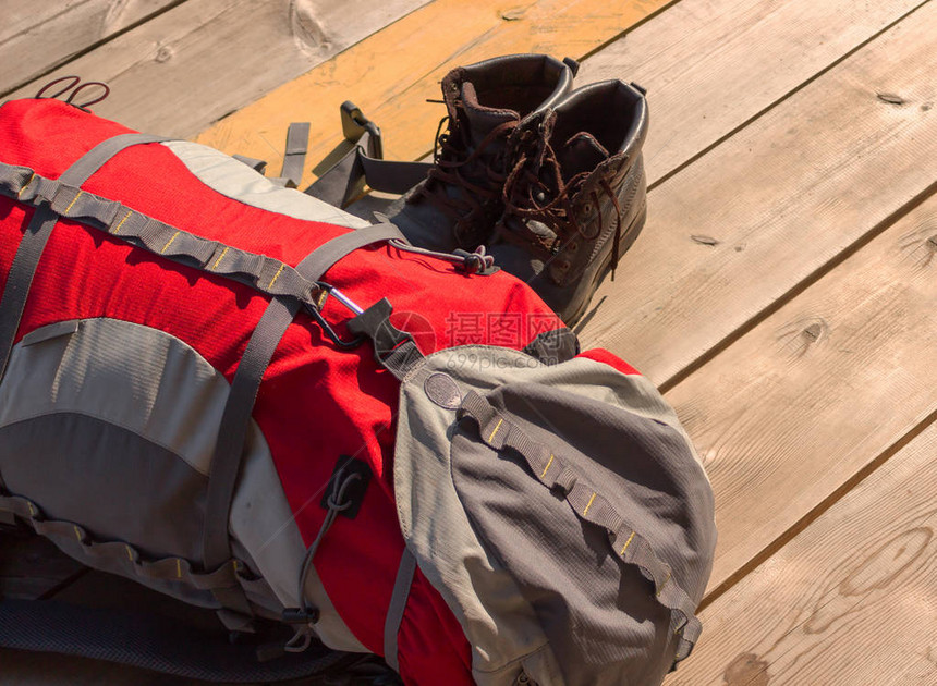 红色的旅游背包和尘土飞扬的旧远足靴图片
