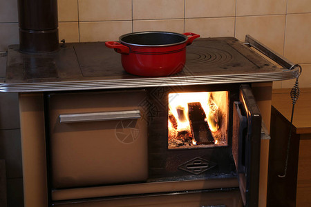 小木屋厨房里旧木柴炉上的红锅图片