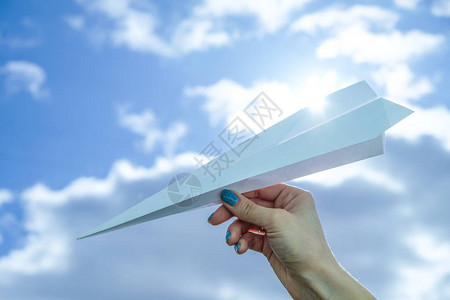 起飞手拿着纸飞机在天空中图片