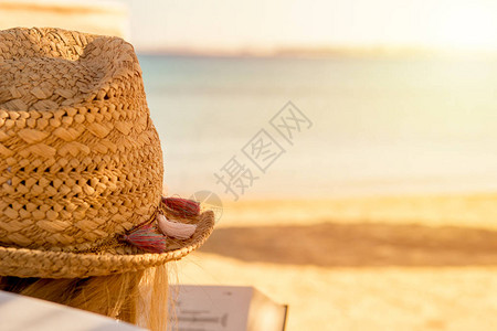戴着草帽的女孩在红海的沙滩上读书图片