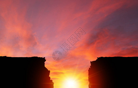在两个悬崖剪影之间的戏剧日落或日出背景自然景图片