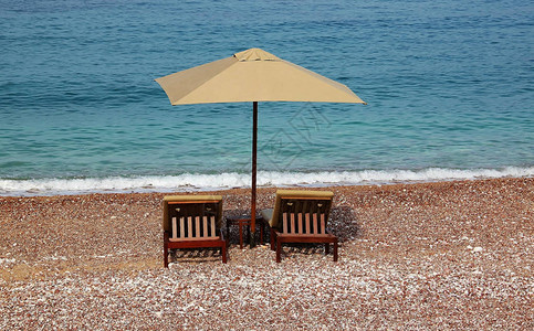 海边的一把沙滩伞和两张沙滩床图片