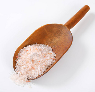 白色背景上的一勺粗粒喜马拉雅盐背景图片