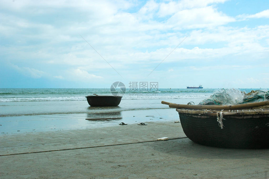 越南的海滩上有两艘篮形渔船一个装满了渔网沙滩上有一对丁字裤图片