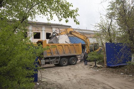 车轮上的挖掘机在自卸卡车的身中装载建筑垃圾和旧建图片