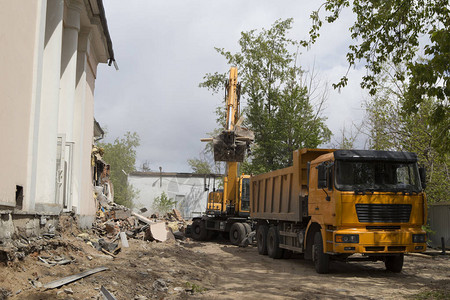 车轮上的挖掘机在自卸卡车的身中装载建筑垃圾和旧建图片