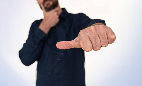 身穿蓝色衬衫的商人用拇指侧身做手势图片