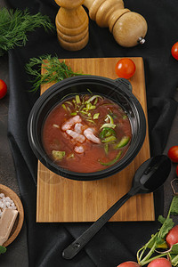 木板上黑碗里的西红柿和鳄梨虾汤图片