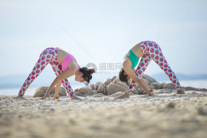 两个女人在沙滩上做瑜伽姿势图片