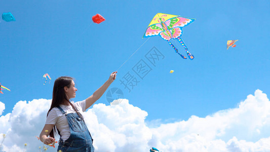 一个年轻怀孕女孩穿泳装发射风筝面对蓝色图片