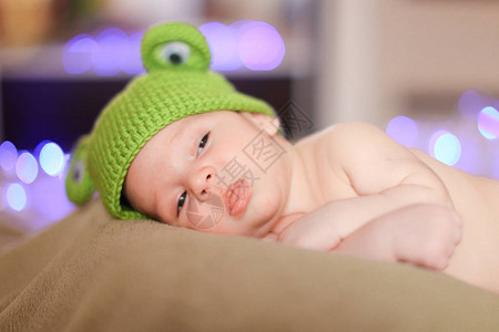 穿着绿帽的可爱小宝躺在壁画背景里新生图片