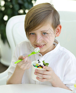 男孩用果浆和巧克力吃冷冻酸奶图片