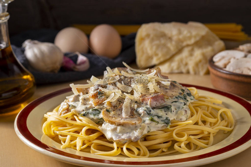 盘子上放着奶油酱信标菠菜和蘑菇的意大利面图片