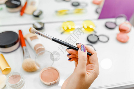 桌子背景上美容师女手中的专业化妆刷化妆品图片
