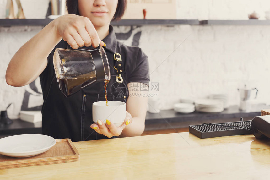 无法辨认的咖啡师在咖啡柜台倒咖啡在她工作的地方穿制服的年轻女孩的画像小企业职业人和服务理图片