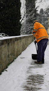 在冬季降雪后从冰冻人行道上铲雪时图片