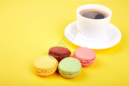 甜品马卡龙或马卡龙配黄色背景的咖啡五颜六色的杏仁饼干蛋糕图片