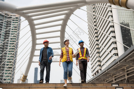亚洲男和美国女经理的快乐工程师团队在曼谷市步行人道上行走图片