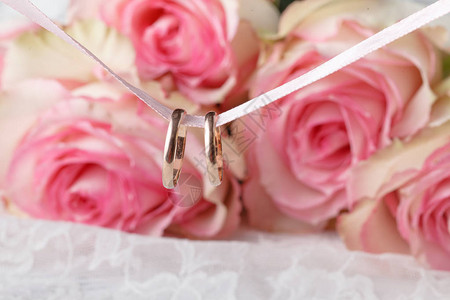 美丽的婚礼花束和戒指在桌子上闪亮地图片